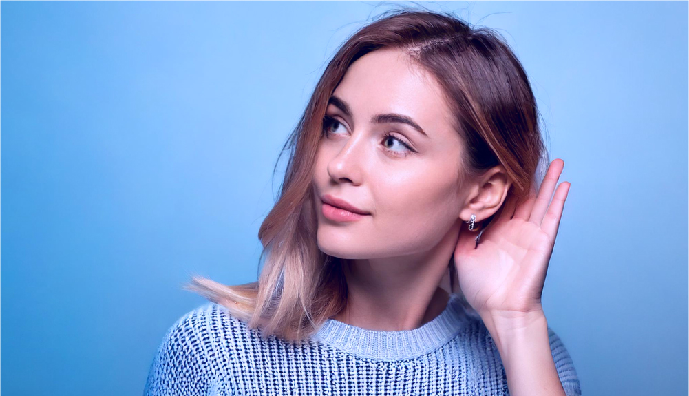 Kobieta nasłuchująca dźwięków – symbol analizy hałasu pompy ciepła i komfortu akustycznego